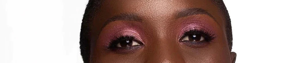 Woman with pink eyeshadow and braided hair against a white background